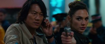 Movie still from “Fast & Furious 6” (2013), directed by Justin Lin – A man on a cell phone next to a woman holding a gun; Close Up shot, Over the shoulder angle
