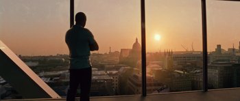 Movie still from “Fast & Furious 6” (2013), directed by Justin Lin – A man standing in front of a window looking out at a city skyline; Wide shot, Low angle