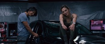 Movie still from “Fast & Furious 6” (2013), directed by Justin Lin – A woman sitting next to another woman in front of a car; Medium shot, Low angle