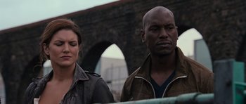 Movie still from “Fast & Furious 6” (2013), directed by Justin Lin – A man and a woman standing next to each other near a bridge; Close Up shot, Over the shoulder angle
