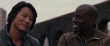 Movie still from “Fast & Furious 6” (2013), directed by Justin Lin – A man and a woman are smiling for the camera; Close Up shot, Low angle