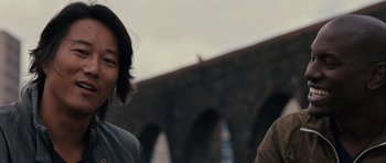 Movie still from “Fast & Furious 6” (2013), directed by Justin Lin – A man and a woman standing next to each other in front of a bridge; Close Up shot, Over the shoulder angle