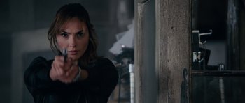 Movie still from “Fast & Furious 6” (2013), directed by Justin Lin – A woman in black jacket holding a gun in front of a wall; Close Up shot, Over the shoulder angle