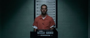 Movie still from “Fast & Furious 6” (2013), directed by Justin Lin – A man in an orange prison uniform sitting in front of a wall; Medium shot, Low angle