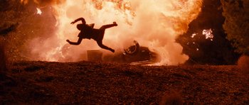 Movie still from “Fast & Furious 6” (2013), directed by Justin Lin – A person jumping in the air in front of a fire; Wide shot, Overhead angle
