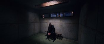 Movie still from “Fast & Furious 6” (2013), directed by Justin Lin – A man sitting on top of a wooden bench in a room; Wide shot, High angle