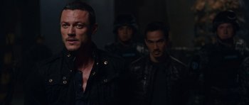 Movie still from “Fast & Furious 6” (2013), directed by Justin Lin – A group of men standing next to each other in a dark room; Medium shot, Over the shoulder angle
