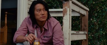 Movie still from “Fast & Furious 6” (2013), directed by Justin Lin – A man sitting on a bench holding a bottle of beer; Close Up shot, Over the shoulder angle