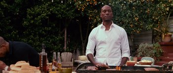 Movie still from “Fast & Furious 6” (2013), directed by Justin Lin – A man standing in front of a grill with food on top of it; Medium shot, Low angle