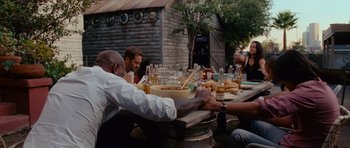Movie still from “Fast & Furious 6” (2013), directed by Justin Lin – A group of people sitting at a table with food; Medium shot, Over the shoulder angle