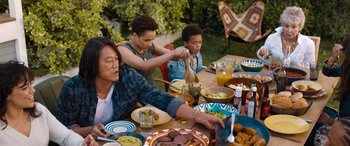 Movie still from “Fast X” (2023), directed by Justin Lin – Three people sitting at a table with plates of food on it; Medium shot, High angle