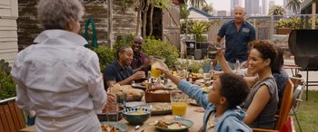 Movie still from “Fast X” (2023), directed by Justin Lin – A group of people sitting at a table with plates of food; Medium shot, Over the shoulder angle