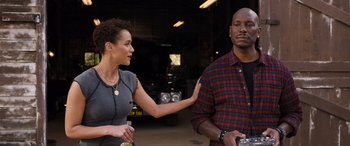 Movie still from “Fast X” (2023), directed by Justin Lin – A man and a woman standing next to each other in front of a car; Medium shot, Over the shoulder angle