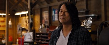 Movie still from “Fast X” (2023), directed by Justin Lin – A person standing in a room wearing a plaid shirt; Close Up shot, Over the shoulder angle