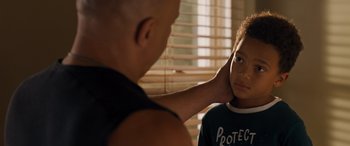 Movie still from “Fast X” (2023), directed by Justin Lin – A young boy is looking at a bald man's face; Close Up shot, Over the shoulder angle
