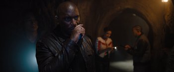 Movie still from “Fast X” (2023), directed by Justin Lin – A man with a microphone in his mouth; Medium shot, Over the shoulder angle