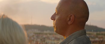 Movie still from “Fast X” (2023), directed by Justin Lin – A bald headed man looking out over a city; Close Up shot, Low angle