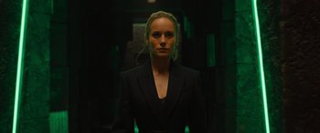 Movie still from “Fast X” (2023), directed by Justin Lin – A woman in a black suit standing in a dark room; Medium shot, Low angle
