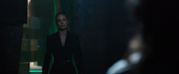 Movie still from “Fast X” (2023), directed by Justin Lin – A woman in a black dress standing in front of a green wall; Medium shot, Over the shoulder angle