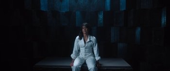 Movie still from “Fast X” (2023), directed by Justin Lin – A woman sitting on top of a bench in a room; Medium shot, High angle