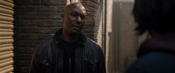 Movie still from “Fast X” (2023), directed by Justin Lin – A man in a leather jacket standing next to a brick wall; Close Up shot, Low angle
