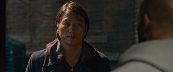 Movie still from “Fast X” (2023), directed by Justin Lin – A man with long brown hair wearing a black jacket; Close Up shot, Over the shoulder angle