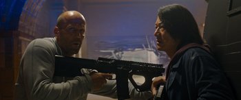 Movie still from “Fast X” (2023), directed by Justin Lin – A man holding a gun in front of another man; Medium shot, Low angle