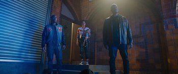 Movie still from “Fast X” (2023), directed by Justin Lin – A group of men standing on steps in a building; Wide shot, Low angle