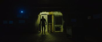 Movie still from “Fast X” (2023), directed by Justin Lin – A man standing in front of an open door in a dark room; Wide shot, Low angle