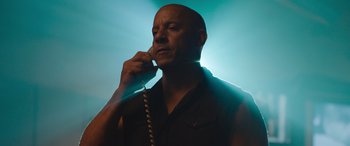 Movie still from “Fast X” (2023), directed by Justin Lin – A man talking on a phone while standing in front of a light; Close Up shot, Low angle