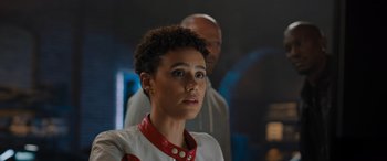 Movie still from “Fast X” (2023), directed by Justin Lin – A woman in a red and white outfit looking at the camera; Close Up shot, Over the shoulder angle