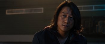 Movie still from “Fast X” (2023), directed by Justin Lin – A person with long black hair; Close Up shot, Over the shoulder angle