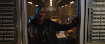 Movie still from “Fast X” (2023), directed by Justin Lin – A man in a leather jacket standing in a room; Medium shot, Low angle