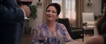 Movie still from “Father of the Bride” (2022), directed by Gary Alazraki – A woman sitting at a table with a glass of red wine; Close Up shot, Over the shoulder angle