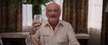 Movie still from “Father of the Bride” (2022), directed by Gary Alazraki – An older man holding a glass of wine in his right hand; Close Up shot, Over the shoulder angle