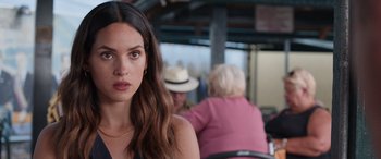 Movie still from “Father of the Bride” (2022), directed by Gary Alazraki – A beautiful young lady sitting at a table with other people; Close Up shot, Over the shoulder angle
