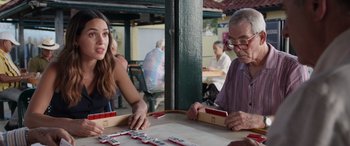 Movie still from “Father of the Bride” (2022), directed by Gary Alazraki – Two people are playing a game of dominoes in an outdoor restaurant; Close Up shot, Over the shoulder angle