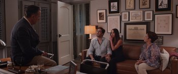 Movie still from “Father of the Bride” (2022), directed by Gary Alazraki – A man and a woman sitting on a brown leather couch; Wide shot, High angle