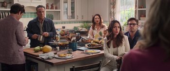 Movie still from “Father of the Bride” (2022), directed by Gary Alazraki – A group of people sitting around a table with food on top of it; Medium shot, Over the shoulder angle