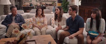 Movie still from “Father of the Bride” (2022), directed by Gary Alazraki – A group of people sitting on top of a white couch; Wide shot, Over the shoulder angle