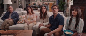 Movie still from “Father of the Bride” (2022), directed by Gary Alazraki – A group of people sitting on top of a white couch; Wide shot, High angle