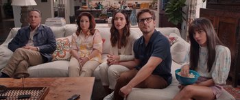 Movie still from “Father of the Bride” (2022), directed by Gary Alazraki – A group of people sitting on top of a white couch; Wide shot, High angle