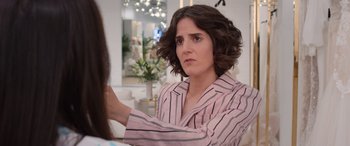 Movie still from “Father of the Bride” (2022), directed by Gary Alazraki – A woman in a pink and black striped shirt is talking to another woman; Close Up shot, Over the shoulder angle