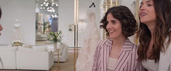 Movie still from “Father of the Bride” (2022), directed by Gary Alazraki – A woman standing in front of a dress in a store; Medium shot, Over the shoulder angle
