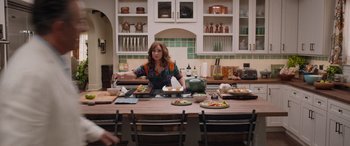 Movie still from “Father of the Bride” (2022), directed by Gary Alazraki – A woman standing at a kitchen counter preparing food; Medium shot, Over the shoulder angle