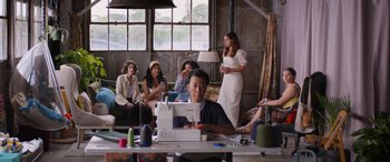 Movie still from “Father of the Bride” (2022), directed by Gary Alazraki – A group of people sitting at a table with sewing machines; Wide shot, Over the shoulder angle