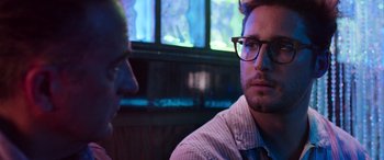 Movie still from “Father of the Bride” (2022), directed by Gary Alazraki – A man wearing glasses sitting next to another man; Close Up shot, Over the shoulder angle