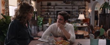 Movie still from “Father of the Bride” (2022), directed by Gary Alazraki – A man sitting at a table with a plate of food in front of him; Medium shot, Over the shoulder angle