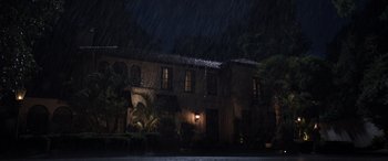 Movie still from “Father of the Bride” (2022), directed by Gary Alazraki – A house that is lit up at night in the rain; Extreme Wide shot, High angle