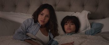 Movie still from “Father of the Bride” (2022), directed by Gary Alazraki – Two people laying in a bed with one of them looking at the camera; Medium shot, Over the shoulder angle